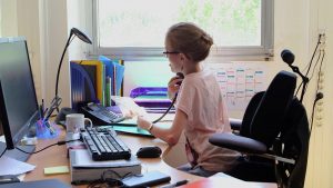 Jeune femme atteinte d'arthrogrypose au travail dans un bureau.