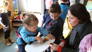 Petite fille atteinte d'arthrogrypose, en salle de maternelle, en motillo pour apprendre à marcher