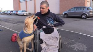 Adulte en fauteil atteint par arthrogrypose, accompagné d'un chien d'aide