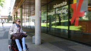 Jeune femme atteinte d'arthrogrypose, se déplaçant en fauteuil roulant à l'université de Grenoble