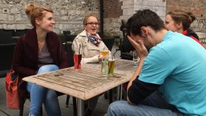 Jeune femme atteinte d'arthrogrypose riant avec ses amis à la terrasse d'un café.