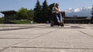 Jeune femme atteinte d'arthrogrypose, en fauteuil devant les montagnes grenobloises